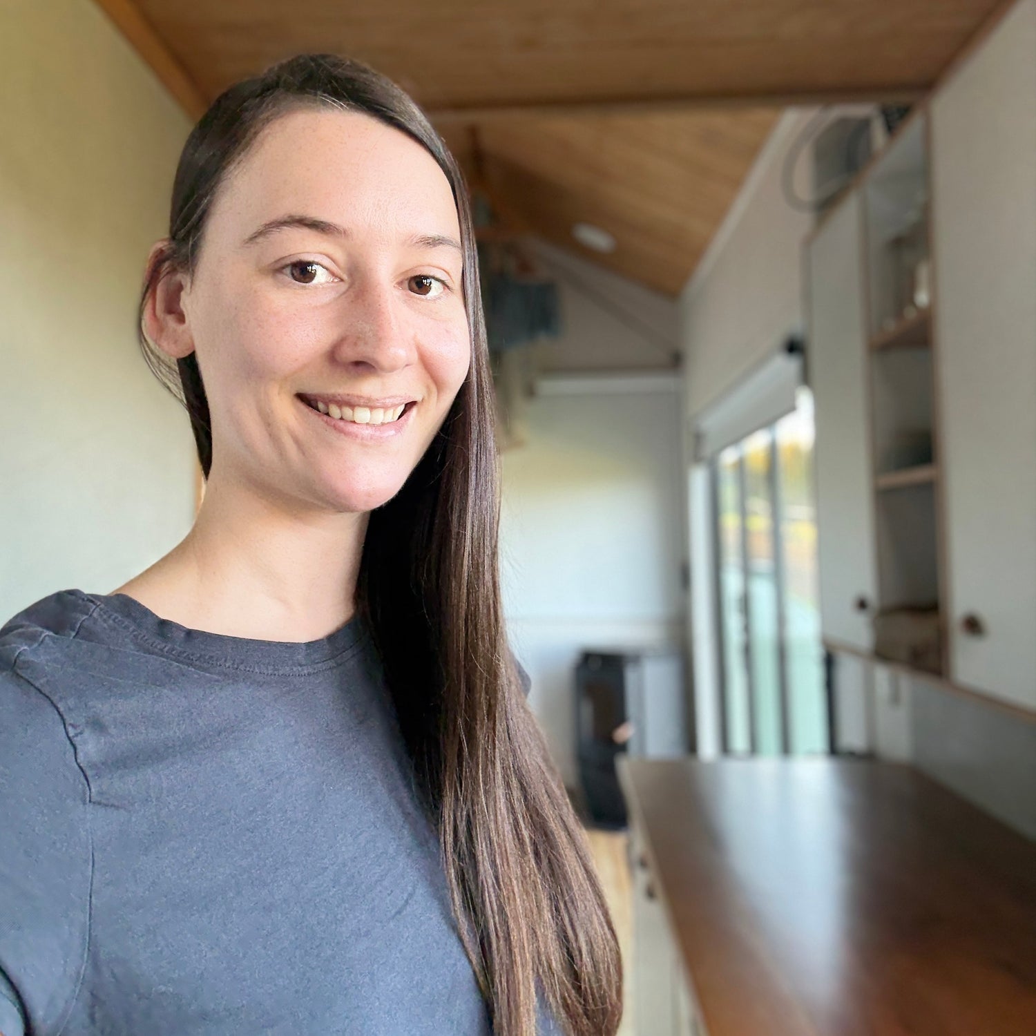 Woman with long hair wearing a gray shirt in an indoor setting